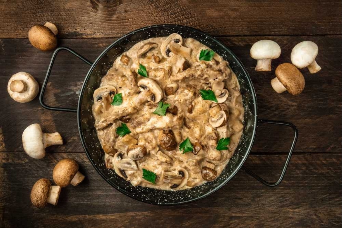 Mushroom risotto in a pan on a wooden table.