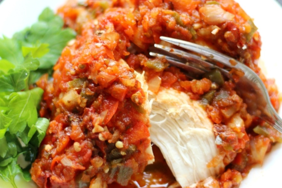 A plate of chicken with sauce and a fork.