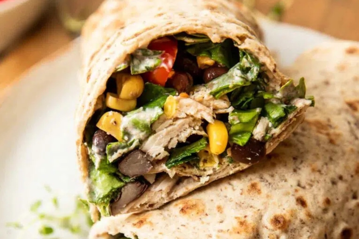 A burrito with black beans and corn on a plate.