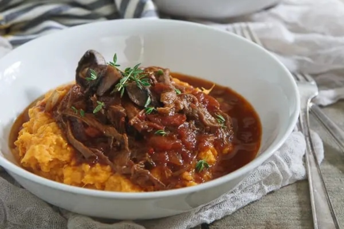 A bowl of mashed potatoes with meat and gravy.