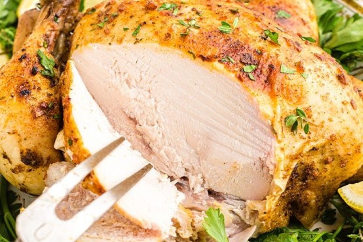 A roasted chicken with lemons and herbs on a platter.