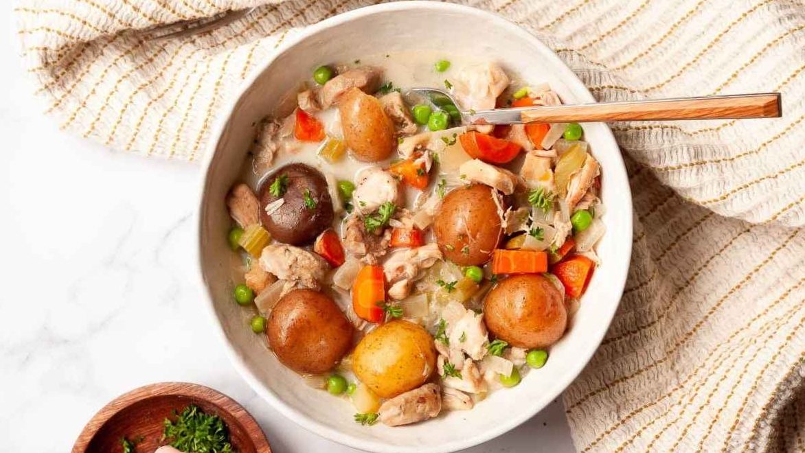 Slow Cooker chicken stew in a white bowl with potatoes and carrots.
