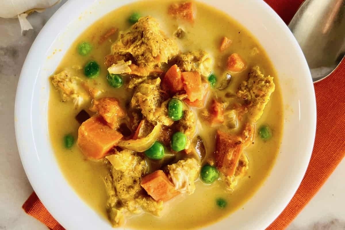 A vegetable-loaded bowl of chicken curry with peas and carrots, perfect for dinner.