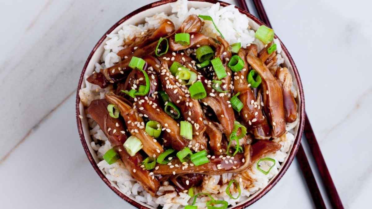 A bowl of asian fried rice with pork, green onions, and dinners.