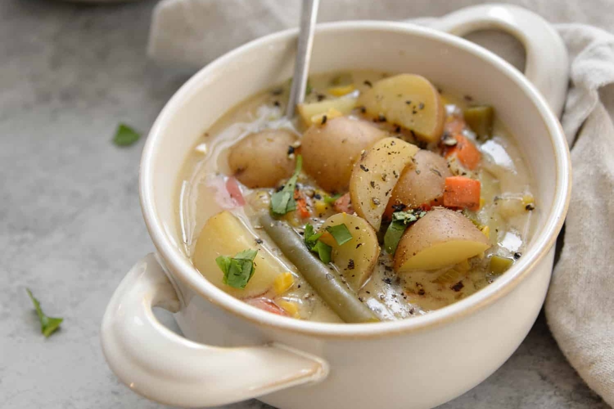 A bowl of vegetable soup with a spoon.