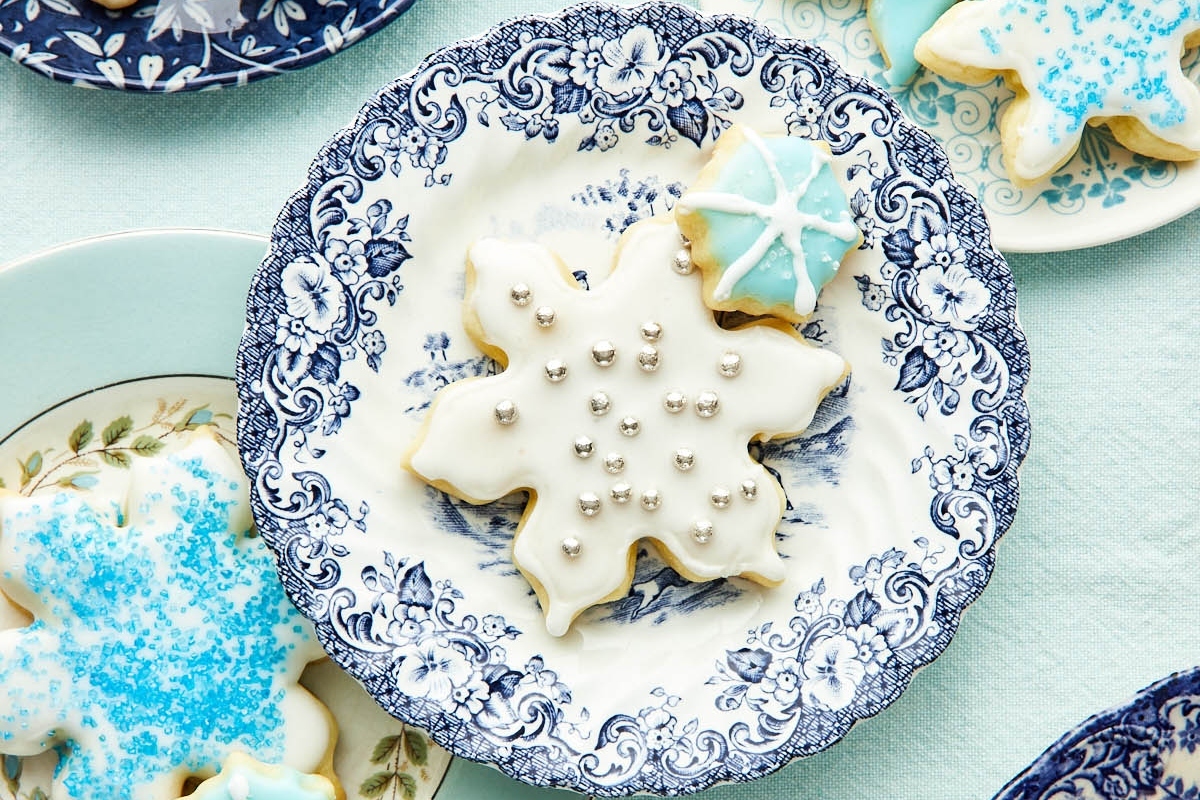 Christmas snowflake cookies on blue and white cut out plates.