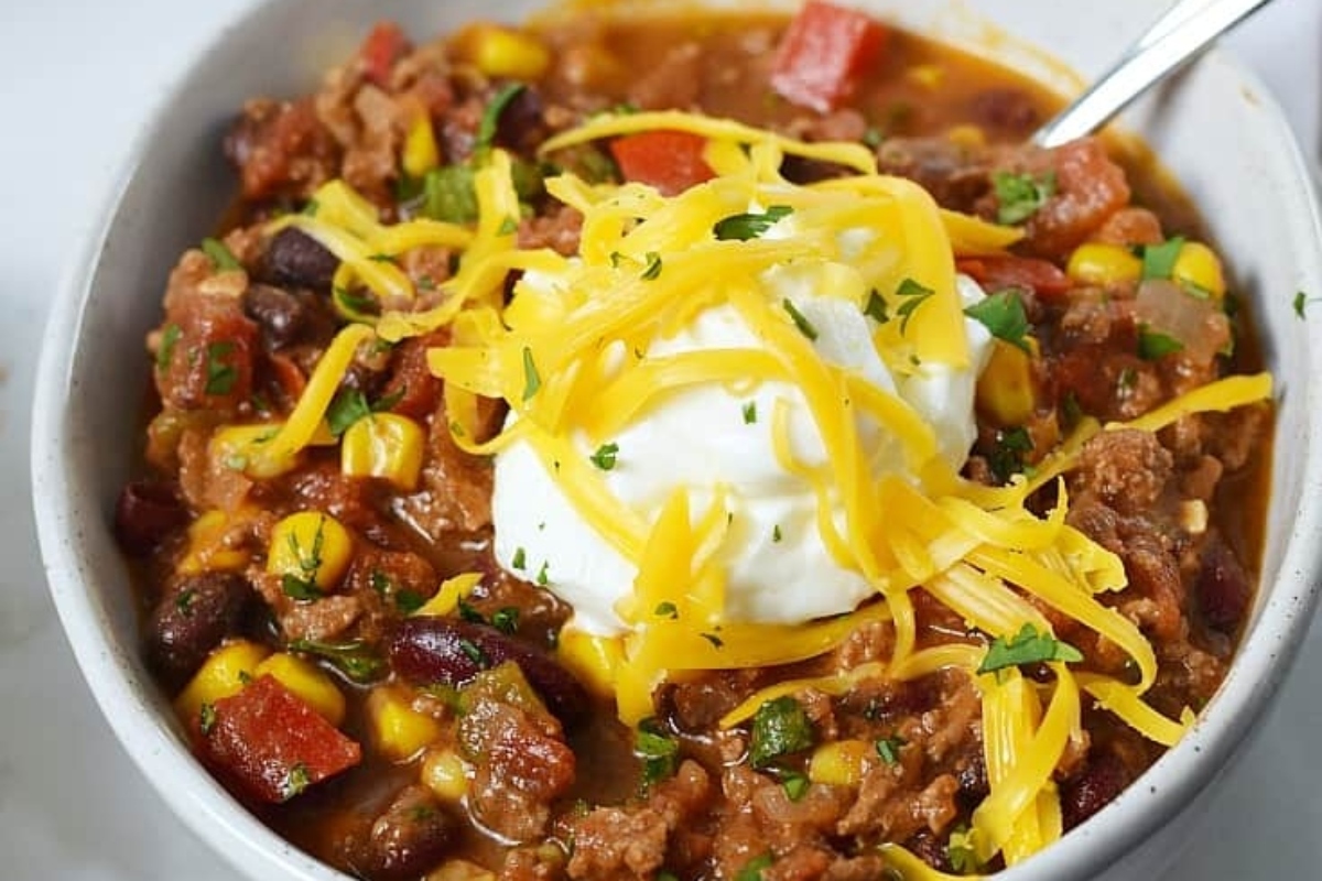 Delicious chili recipes in a bowl with sour cream and corn.