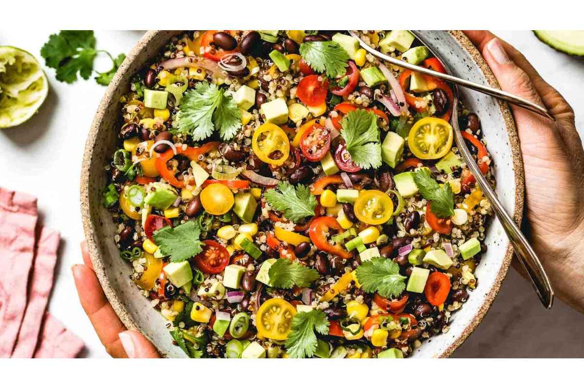 A person is holding a high protein quinoa salad.