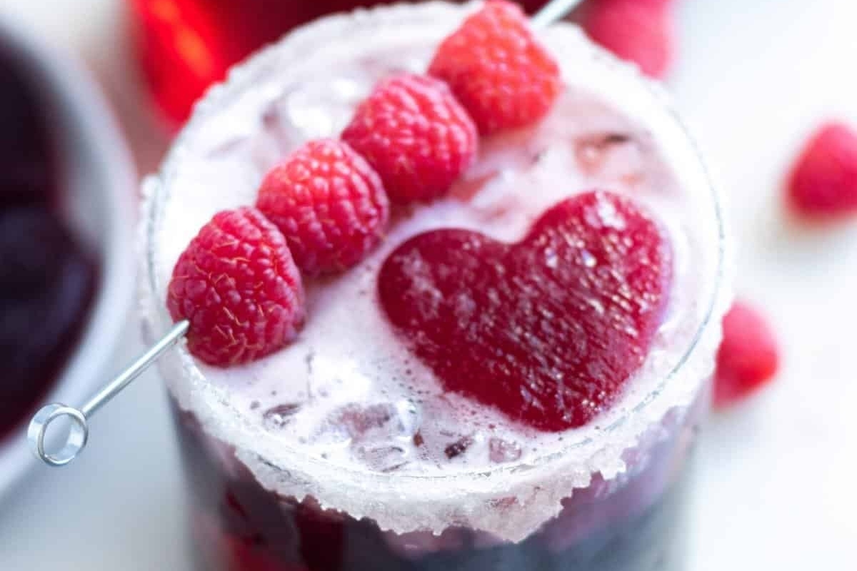 A Valentine's Day cocktail featuring raspberries garnished with a heart-shaped straw.