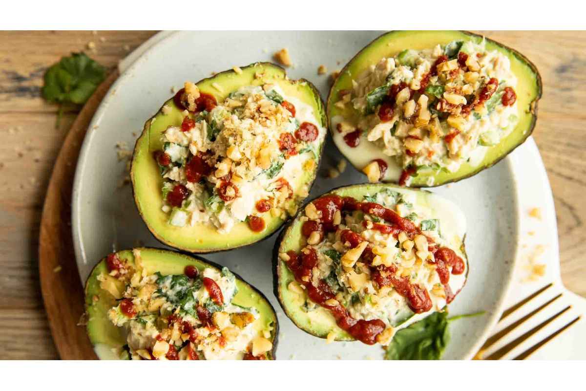 Four healthy avocados stuffed with spinach and cheese on a plate.