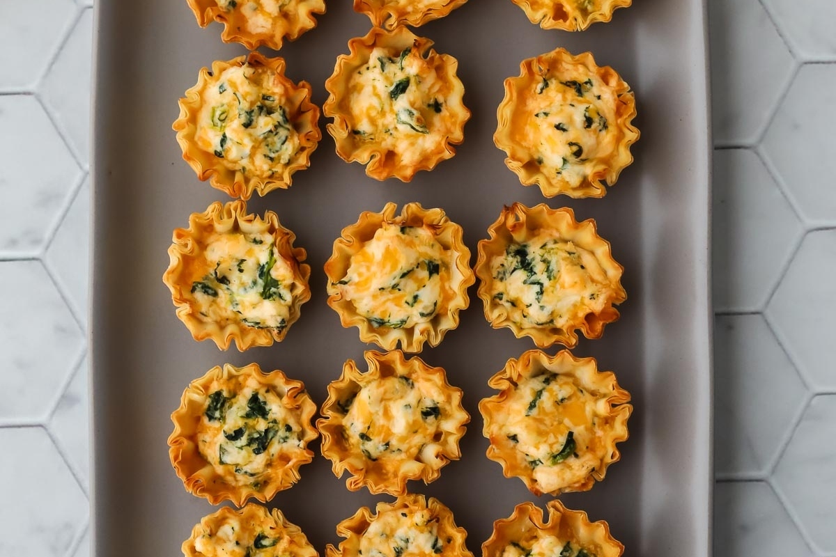 Bite Sized cheesy spinach mini quiches on a tray.