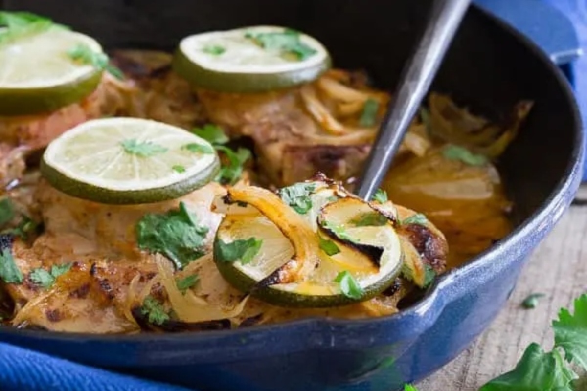 Mexican chicken thighs cooked in a skillet with limes and onions.