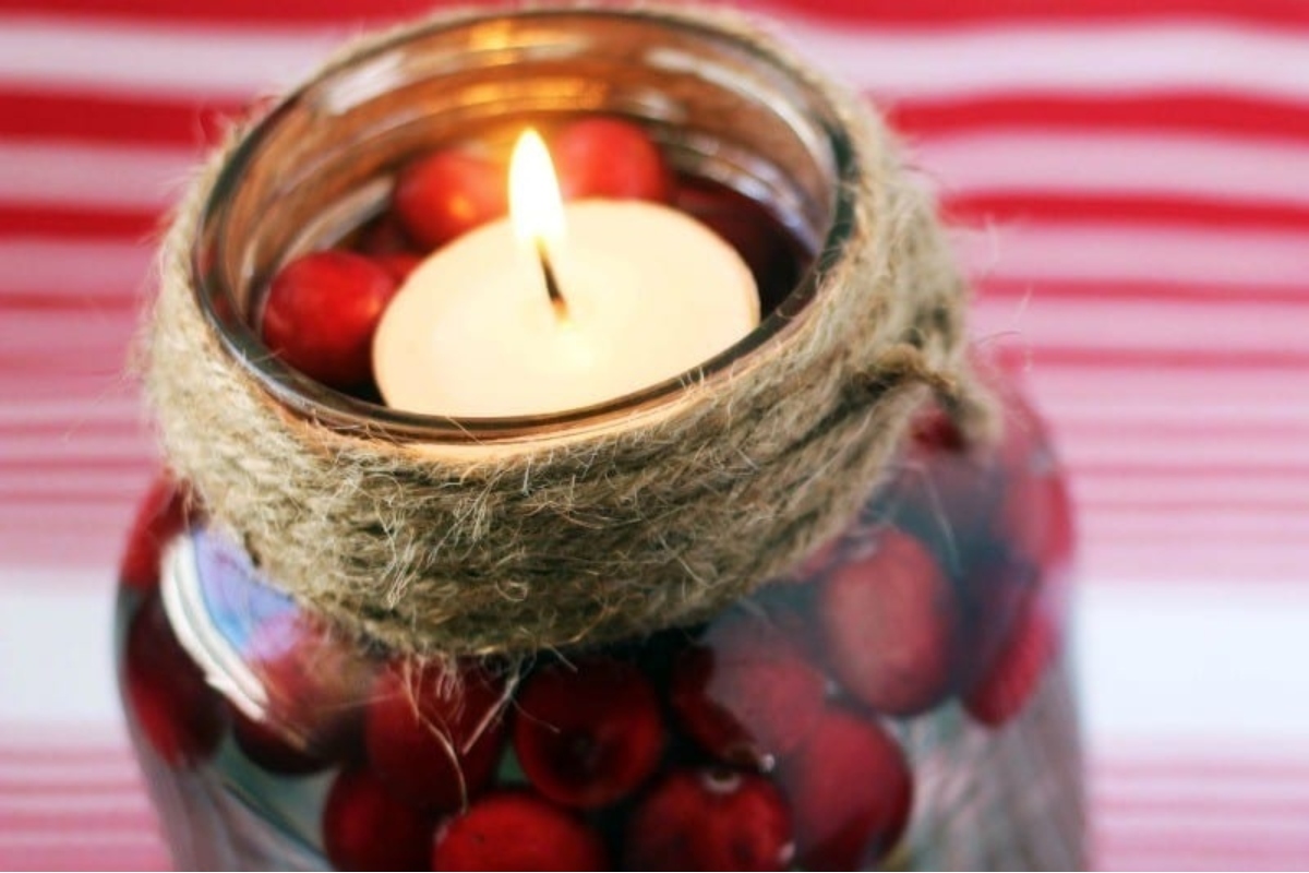 A jar filled with cranberries and a candle, ideal for gift-giving.