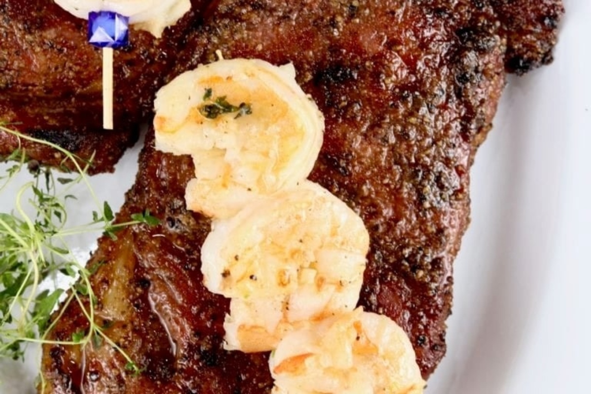 Surf and turf - Grilled steak with shrimp and thyme on a plate.