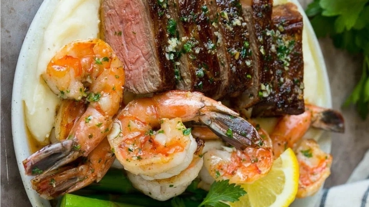 A delectable combination of steak and shrimp, served alongside creamy mashed potatoes, perfect for a romantic Valentine's Day dinner.