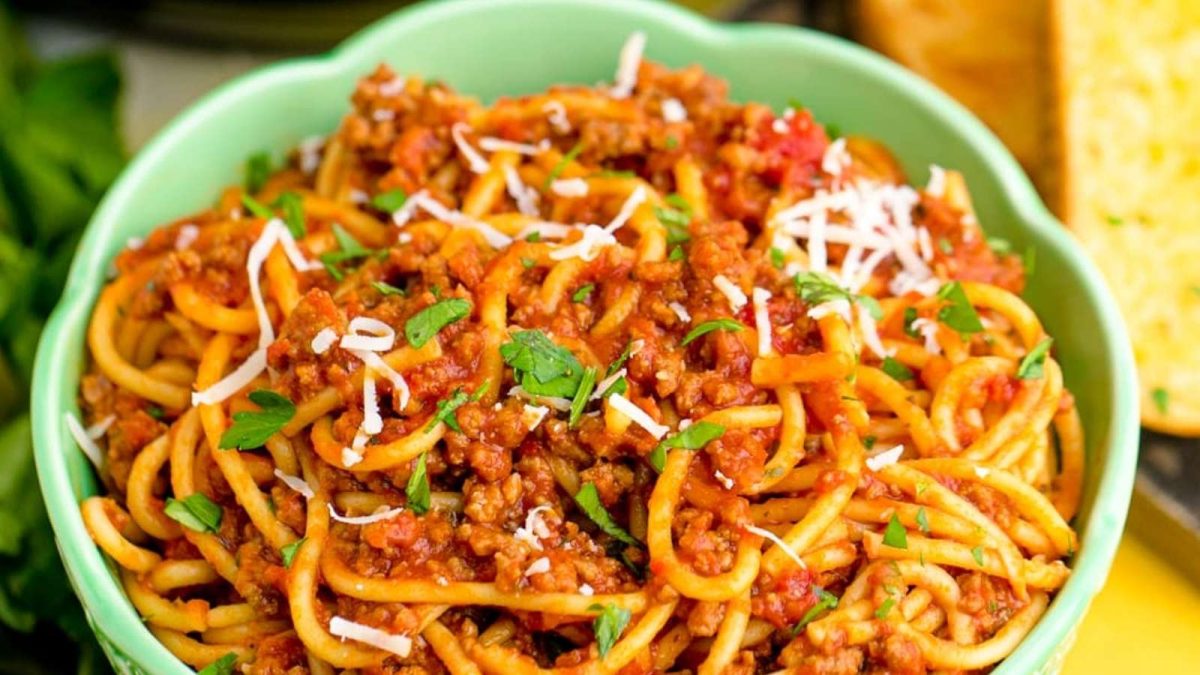 Spaghetti with meat sauce in a green bowl.