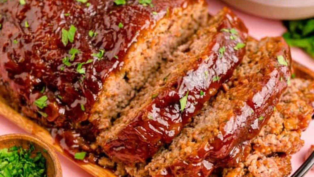 A slice of meatloaf on a wooden cutting board.