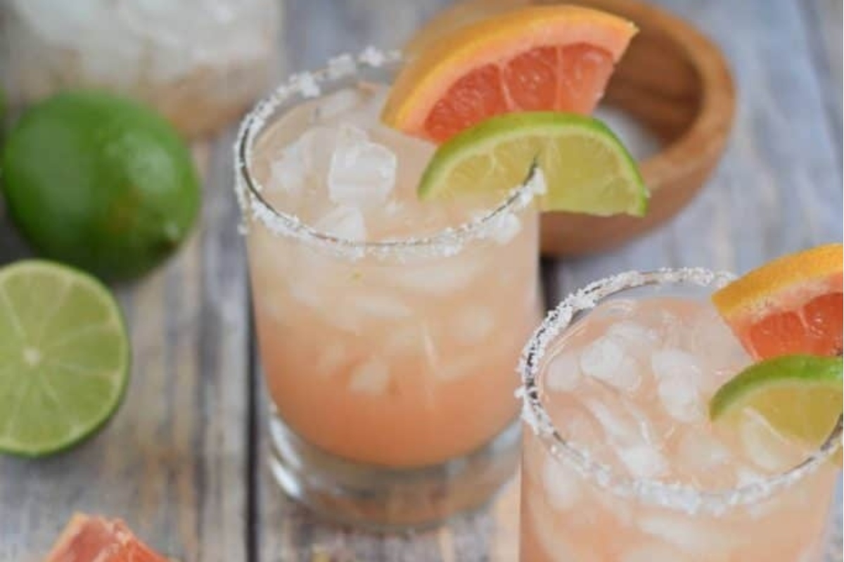 Two Valentine's Day cocktails - grapefruit margaritas garnished with lime and lime wedges.