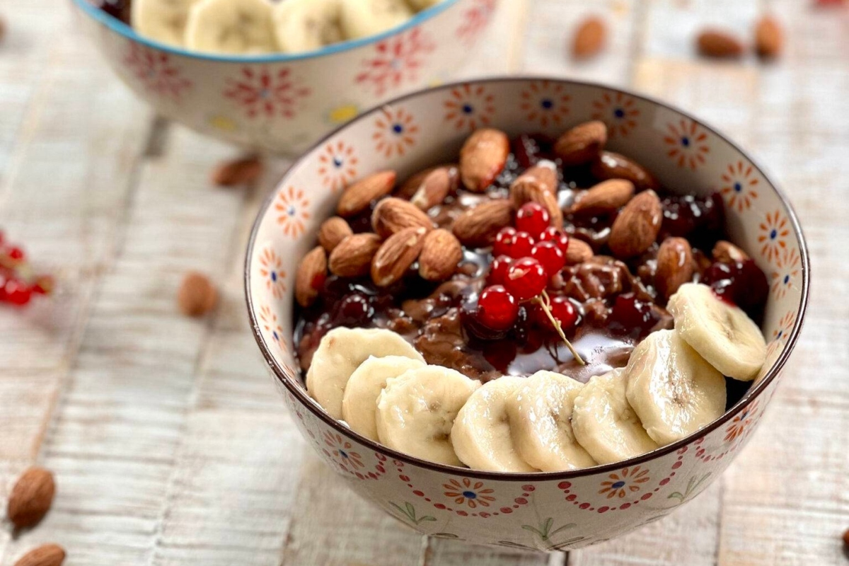 A healthy breakfast of oatmeal topped with bananas, nuts and berries.
