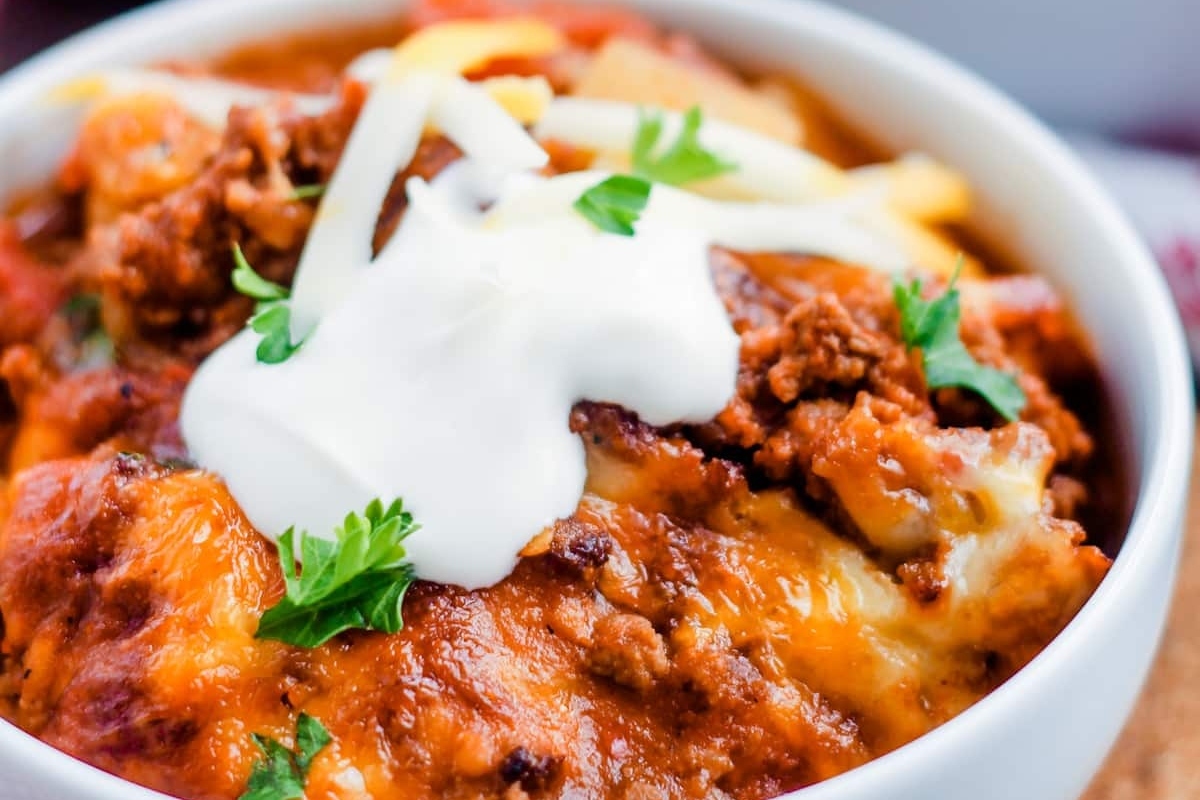 A savory bowl of chili topped with melted cheese and a dollop of sour cream, perfect for cozy dinners or Taco Night.