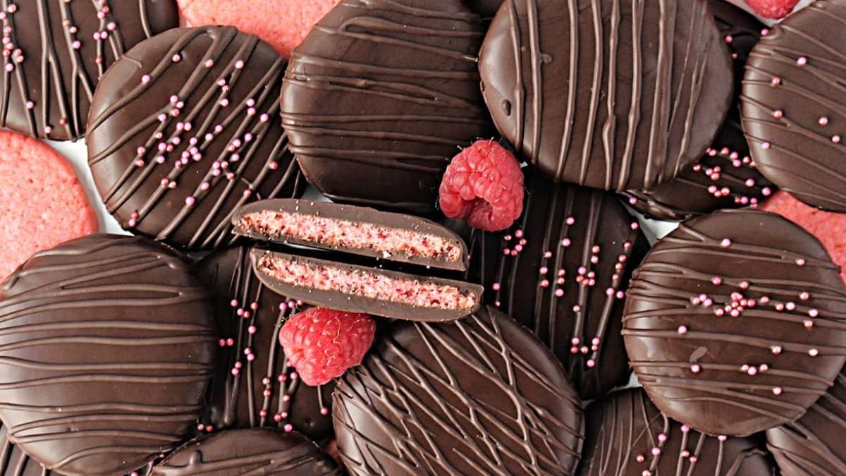 Indulge in a delectable stack of chocolaty cookies adorned with mouthwatering raspberries and irresistible sprinkles.