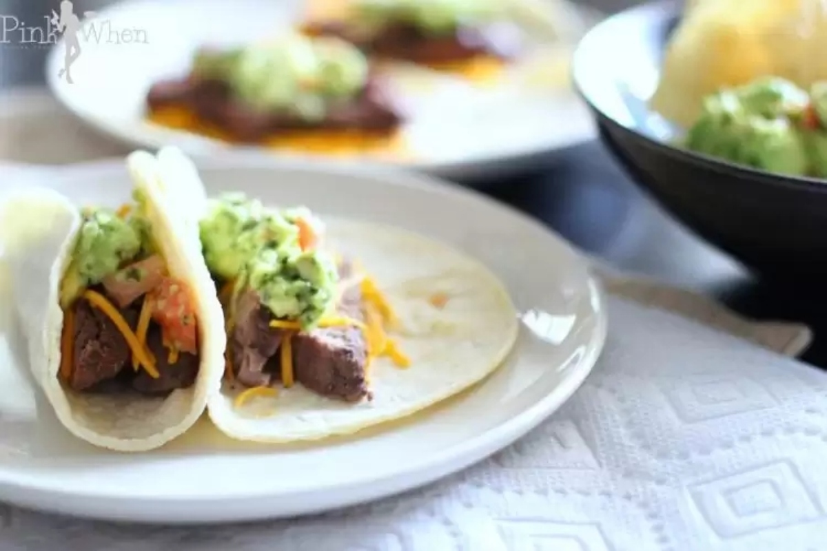 Two tacos on a plate with guacamole for a Taco Night dinner.