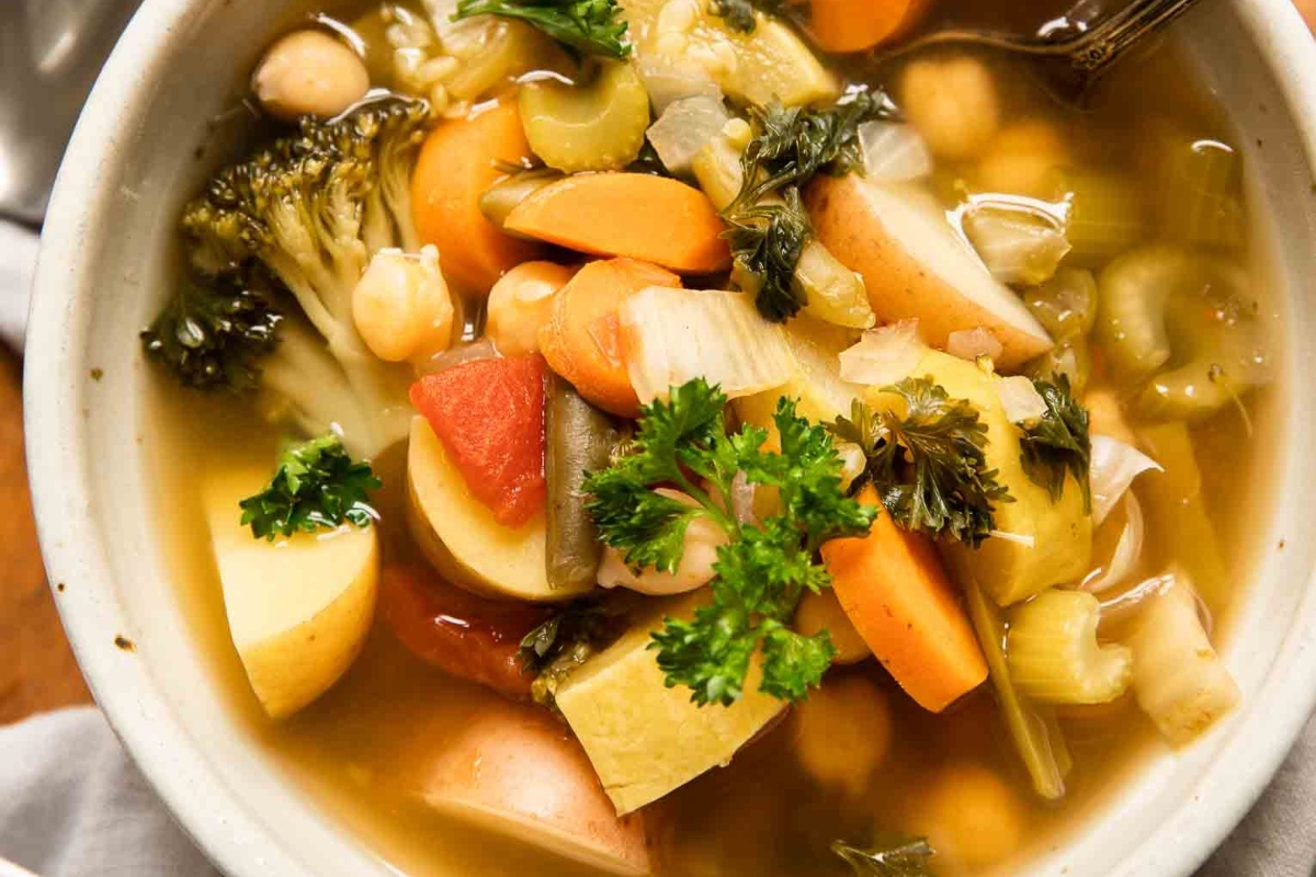 Explore delectable vegetable soup recipes with this satisfying bowl of soup accompanied by a handy spoon.