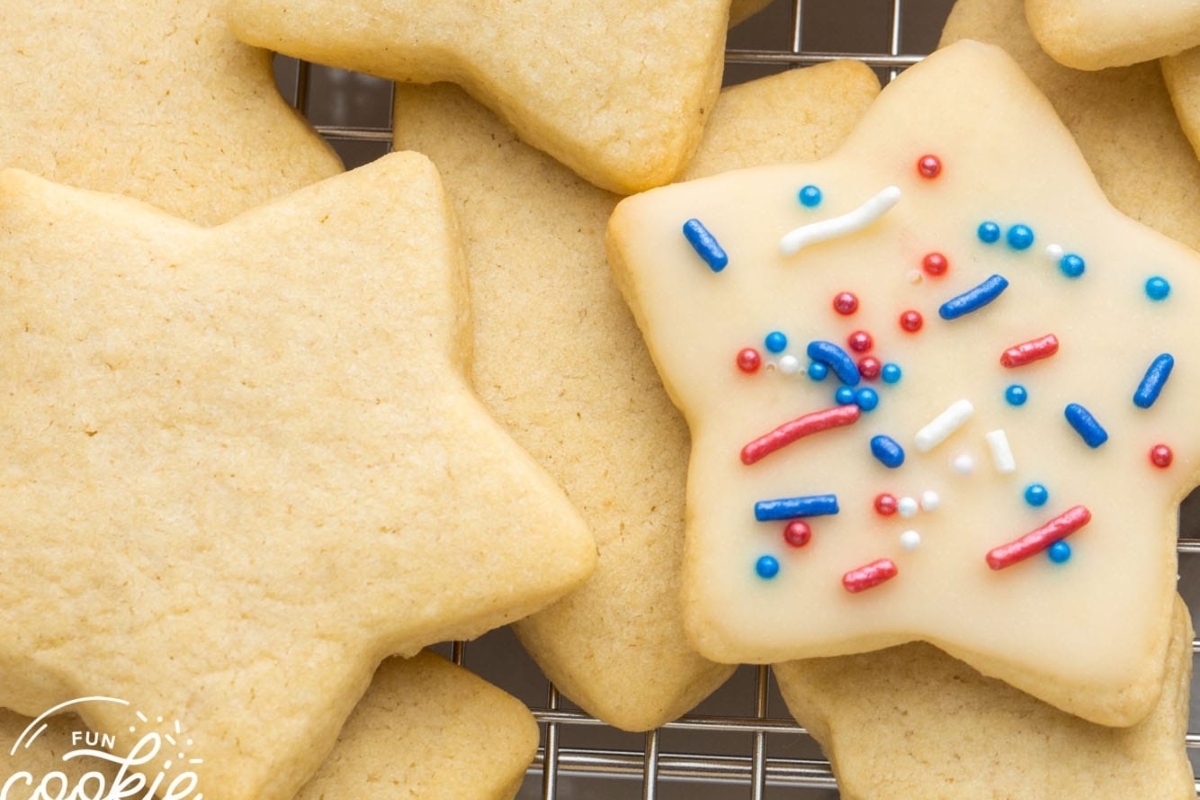Festive Christmas sugar cookies, cut out in star shapes, covered in colorful sprinkles resting on a cooling rack.