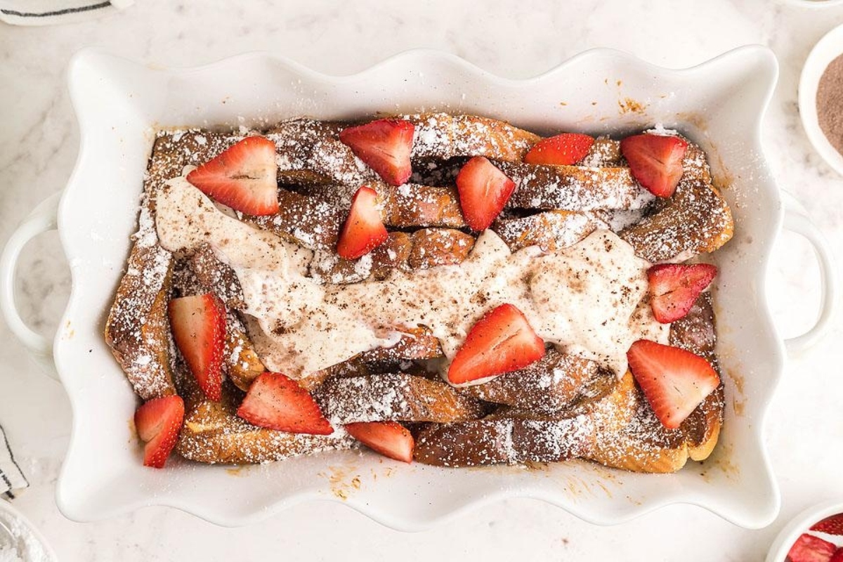 A sweet dish of French toast garnished with strawberries and a dusting of powdered sugar.