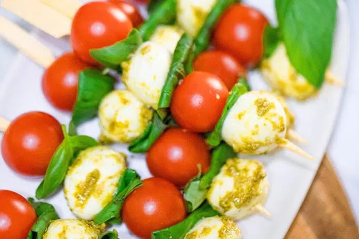 Bite-sized pesto mozzarella skewers with tomatoes and basil perfect for game day.