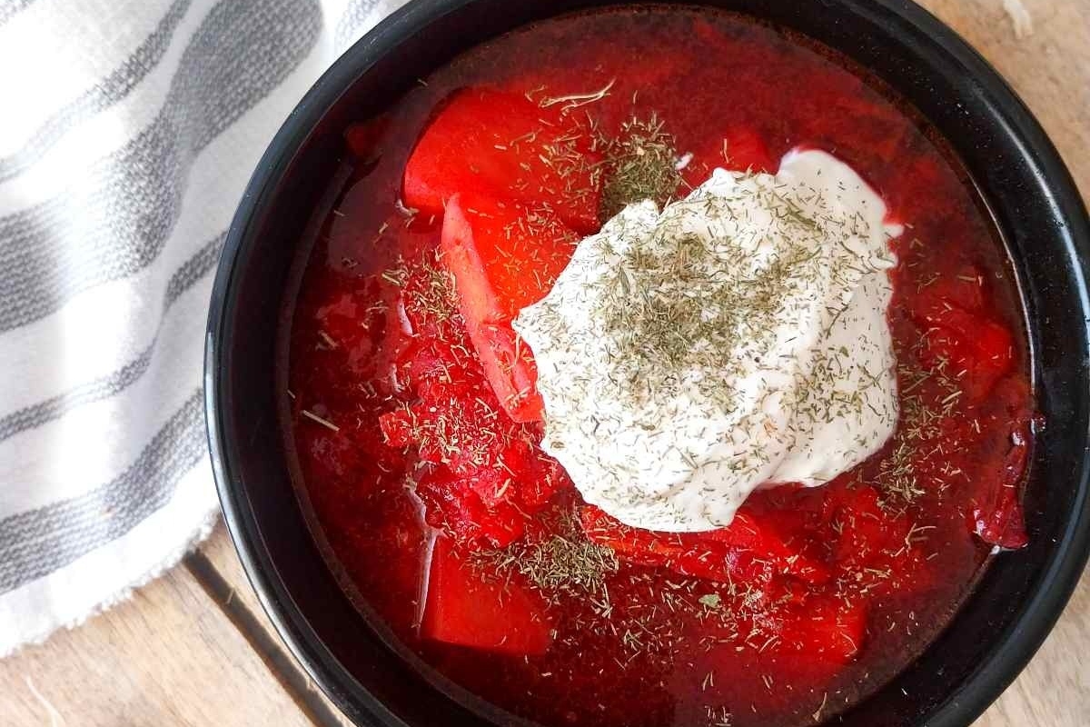 A bowl of red stew with sour cream.