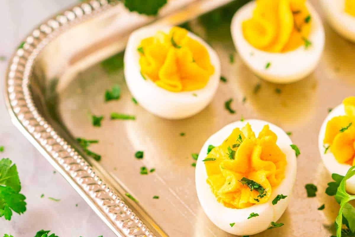Deviled eggs with truffle oil on a silver tray with parsley.