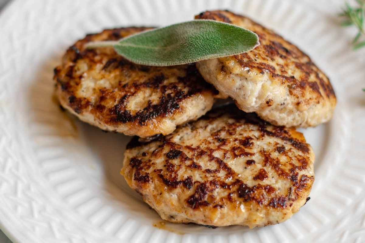 A nutritious and high protein dish featuring flavorful turkey patties served on a pristine white plate, garnished with fresh sage sprigs.