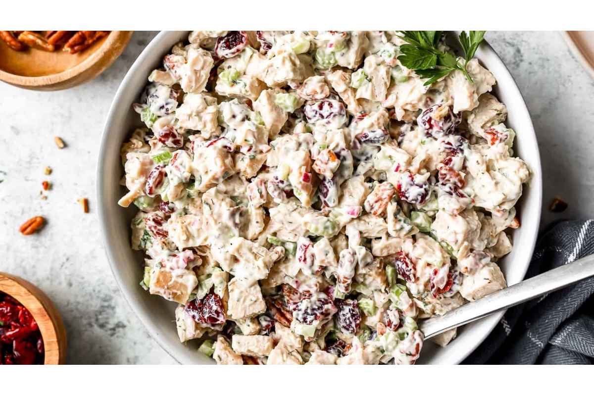 High protein chicken salad with cranberries and pecans in a white bowl - the perfect healthy lunch option.