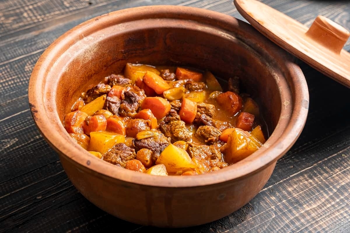 Stew Recipes cooked in a clay pot on a wooden table.