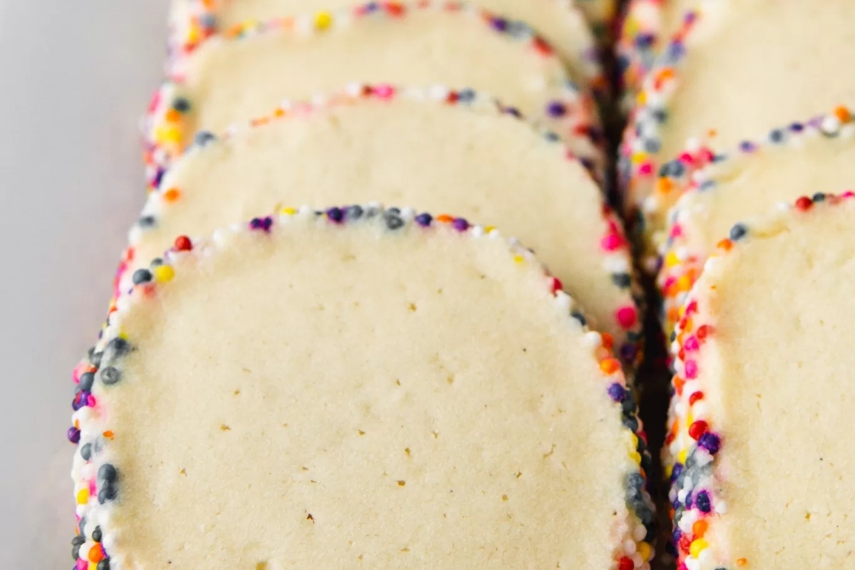 Freezable sugar cookies decorated with Christmas sprinkles, displayed on a white plate.