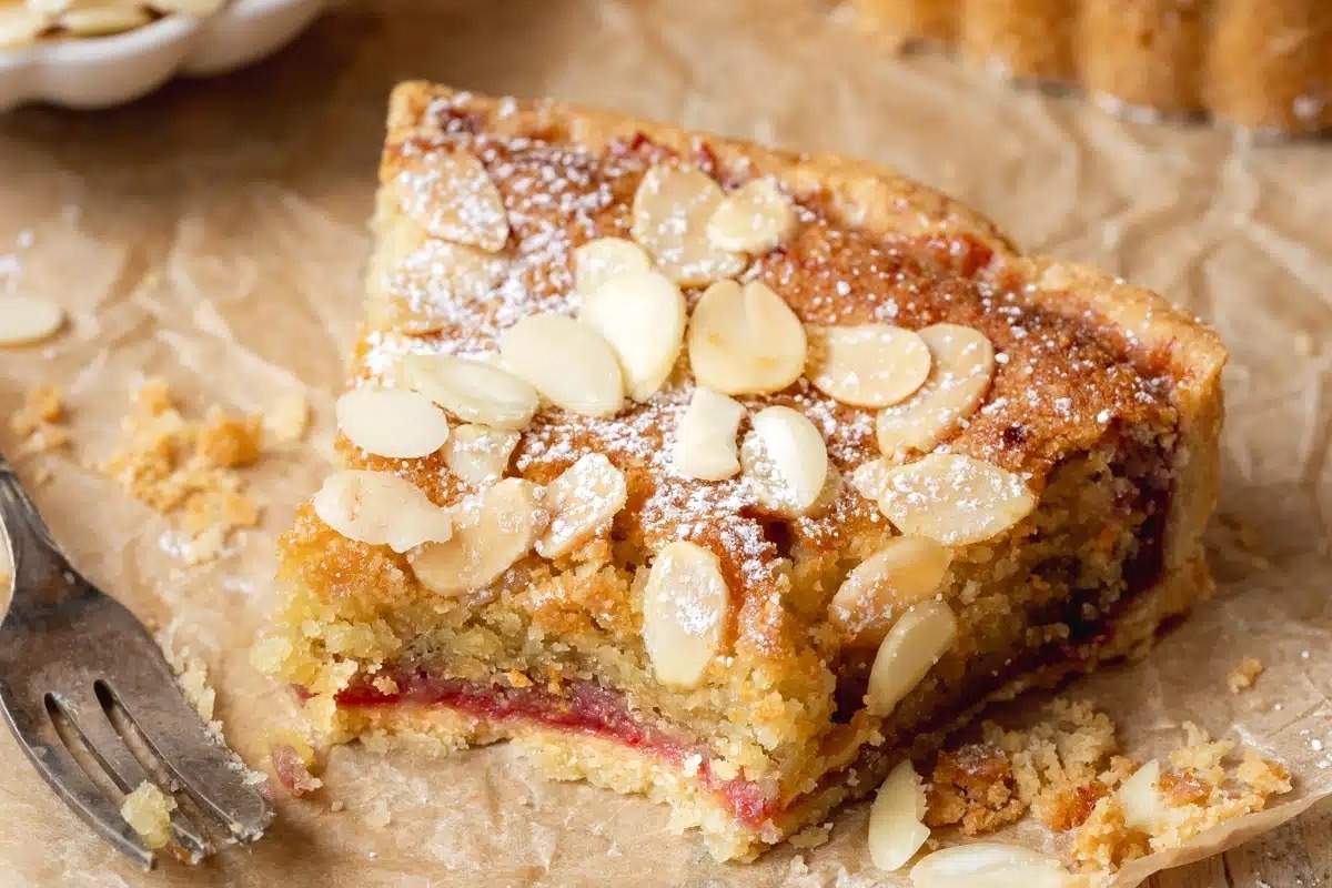 A delectable raspberry almond tart delicately placed on a piece of paper, enticing all with its sweet aroma and mouthwatering appearance.