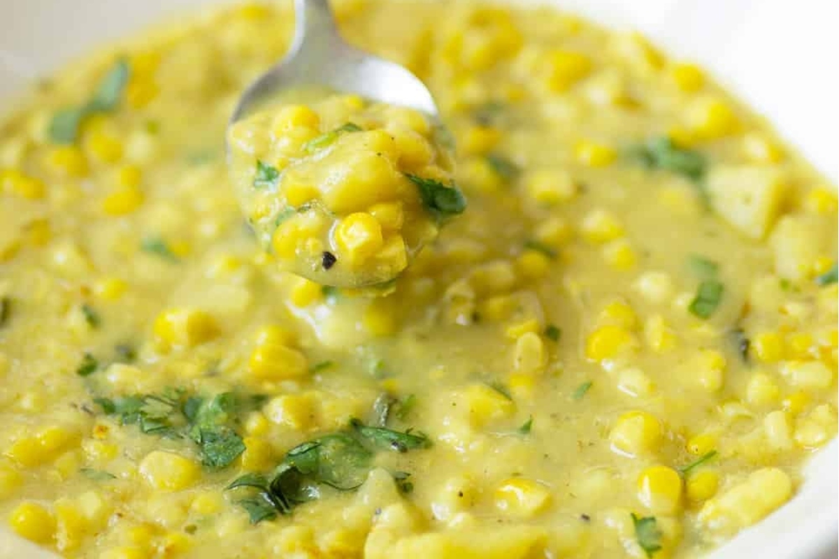 A spoonful of corn chowder in a white bowl.