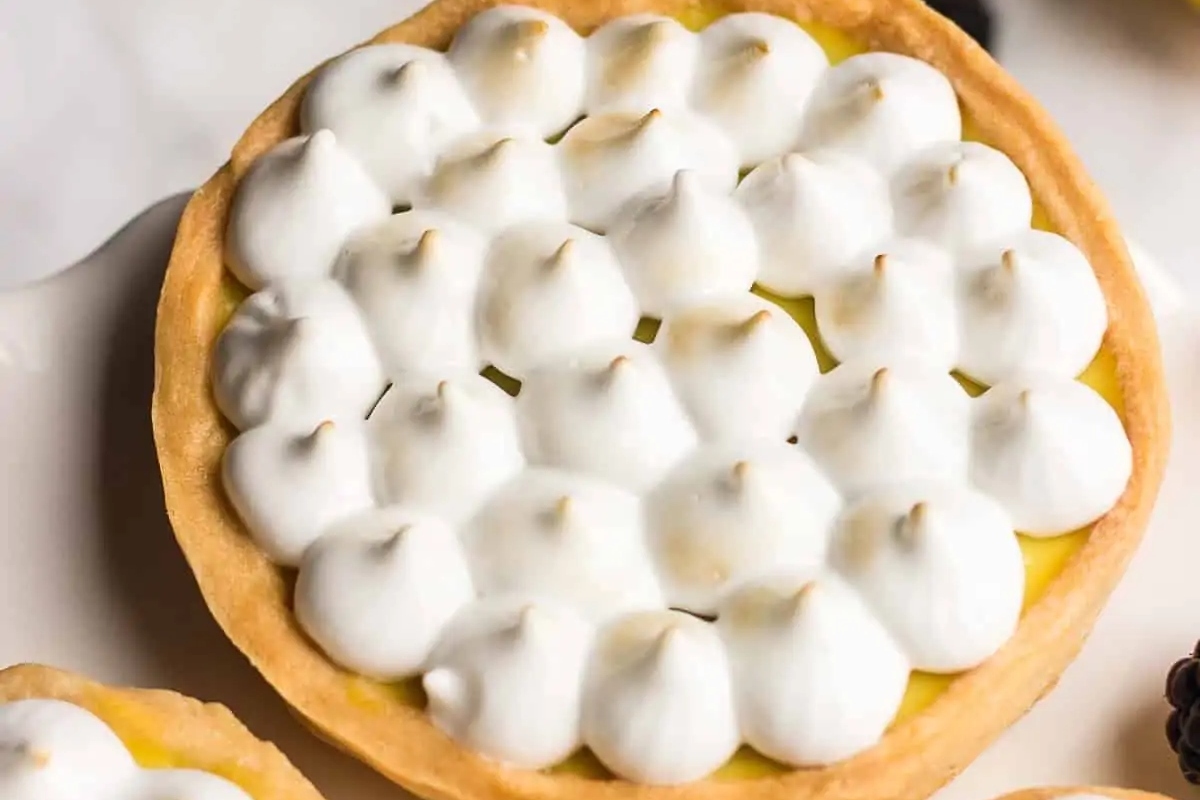 Lemon meringue tarts on a white plate, perfect for those in search of tart recipes.