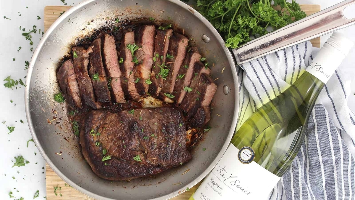 A romantic Valentine's Day dinner featuring a sizzling steak in a pan, accompanied by a tantalizing bottle of wine.