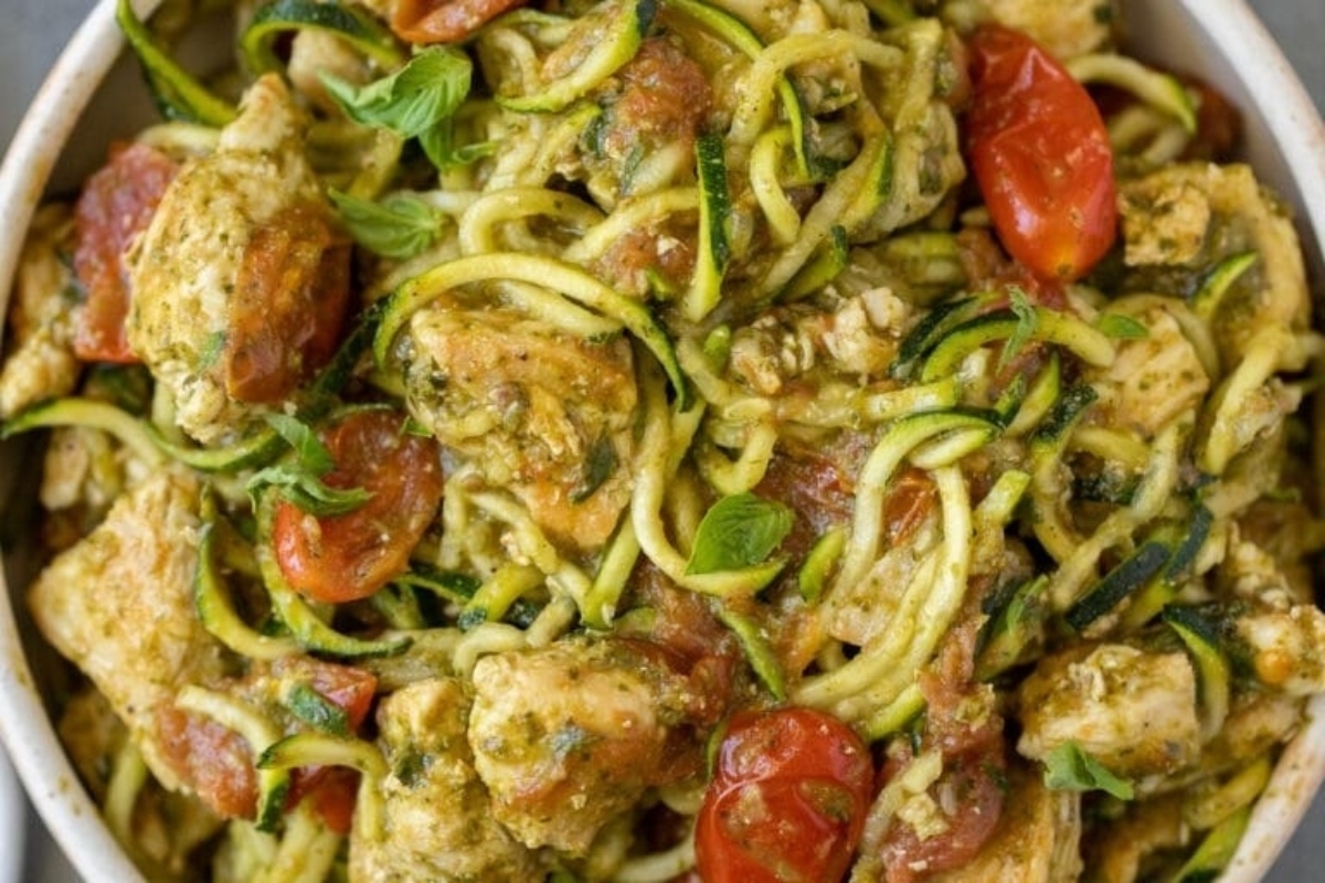 Chicken pesto zucchini noodles in a white bowl, perfect for spiralizer recipes.