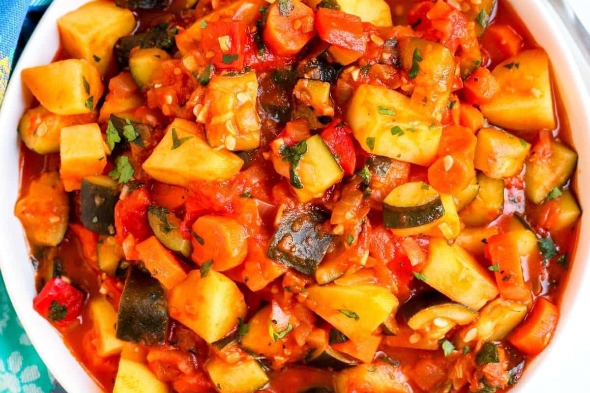 A white bowl with vegetables and tomatoes in a delicious stew.