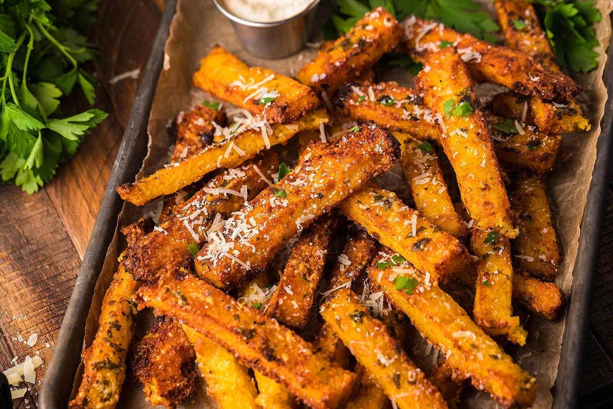 Roasted sweet potato fries on a tray with parsley and parmesan, drizzled with truffle oil.
