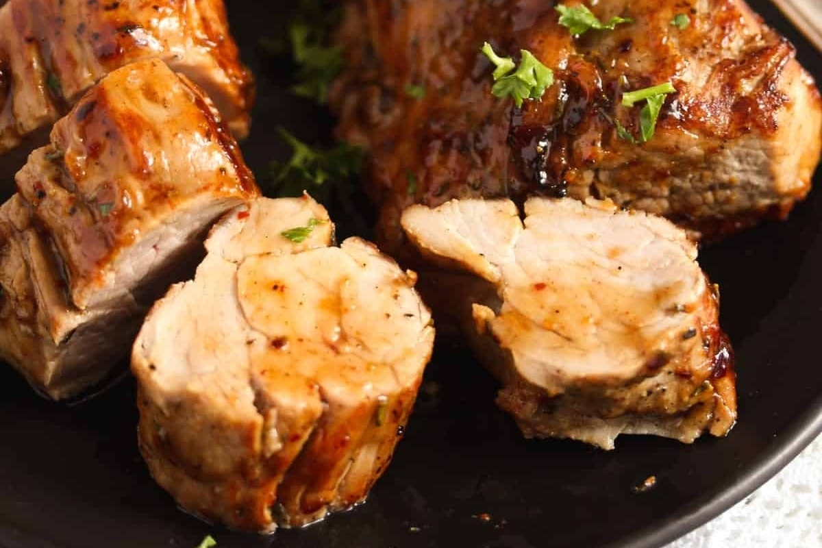 Simple yet elegant, sliced pork tenderloin is beautifully presented on a sleek black plate.
