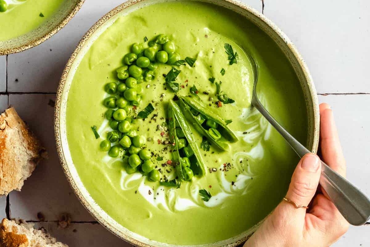 A bowl of green pea soup recipe with a spoon.