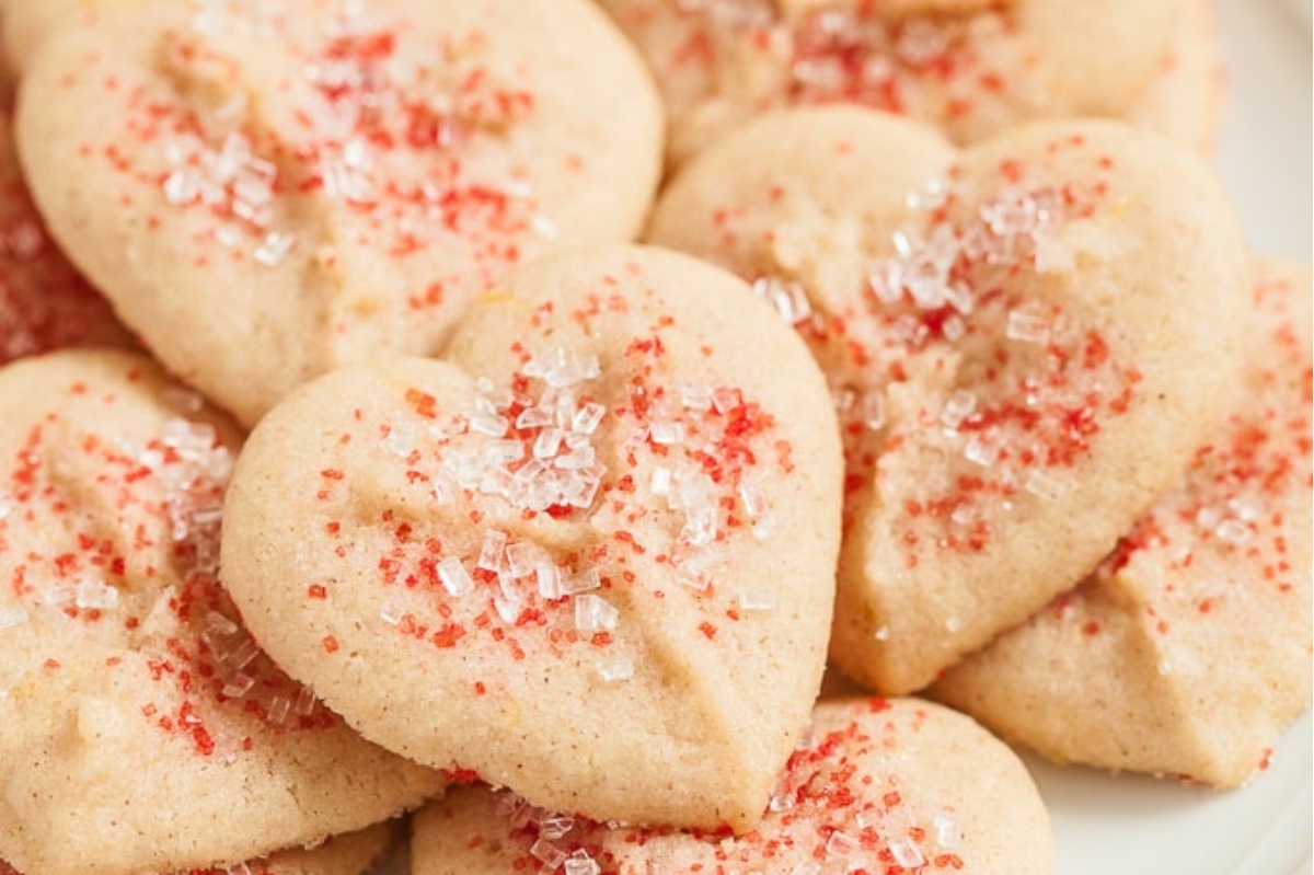Heart shaped cookies adorned with colorful sprinkles, displayed on a festive Valentine's Day plate.