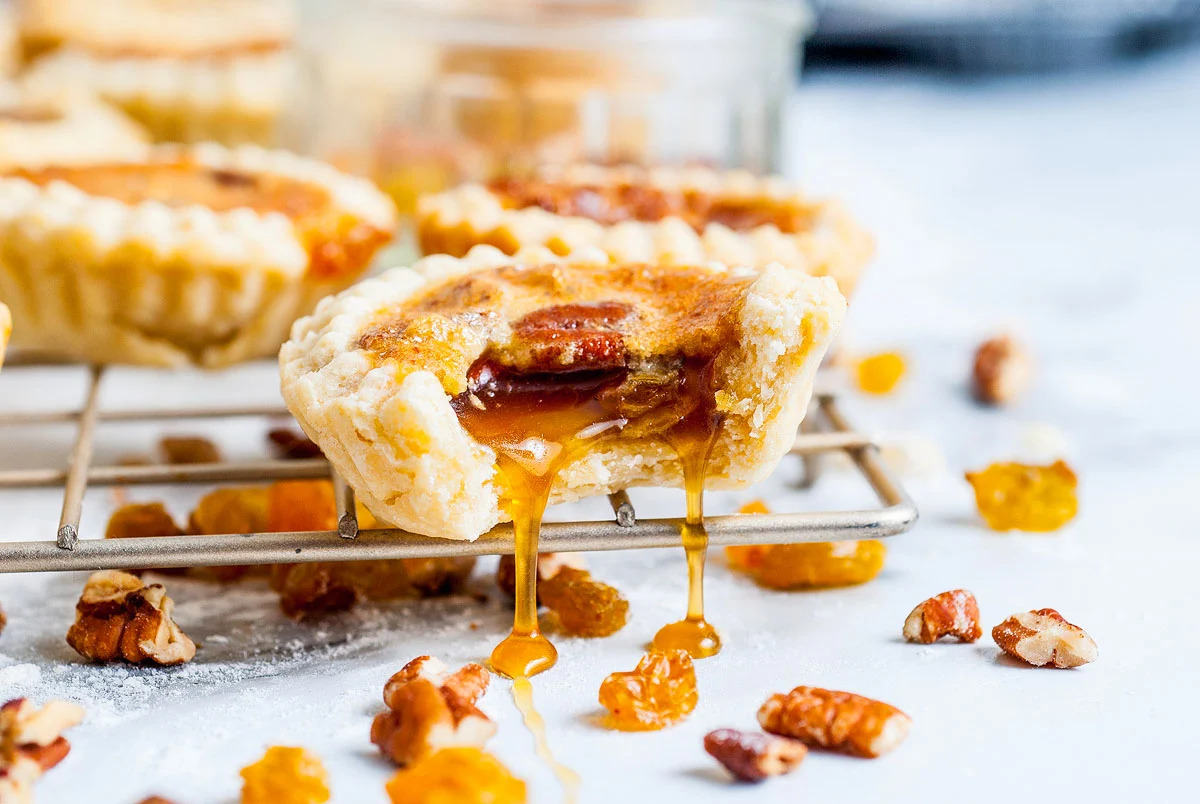 Explore delectable tart recipes featuring caramel and pecans in a tray of mini tarts.