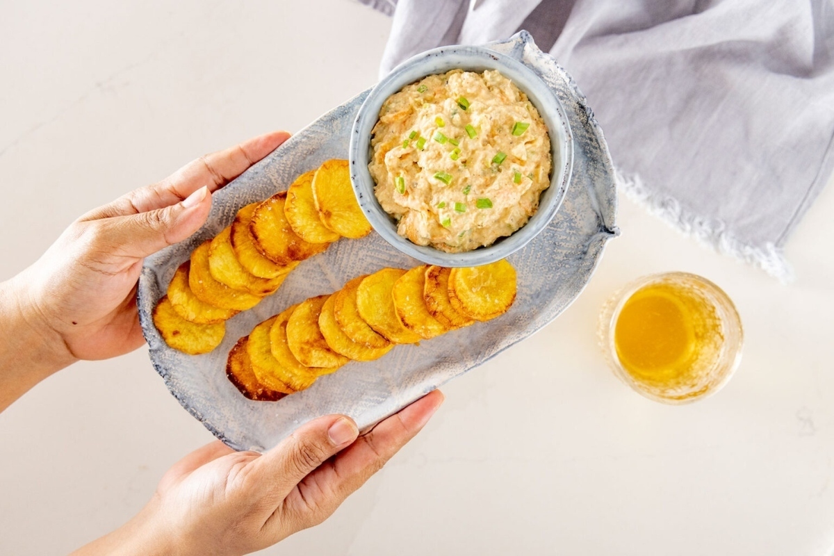The easiest game day recipe - a person holding a plate with potato chips and dip.