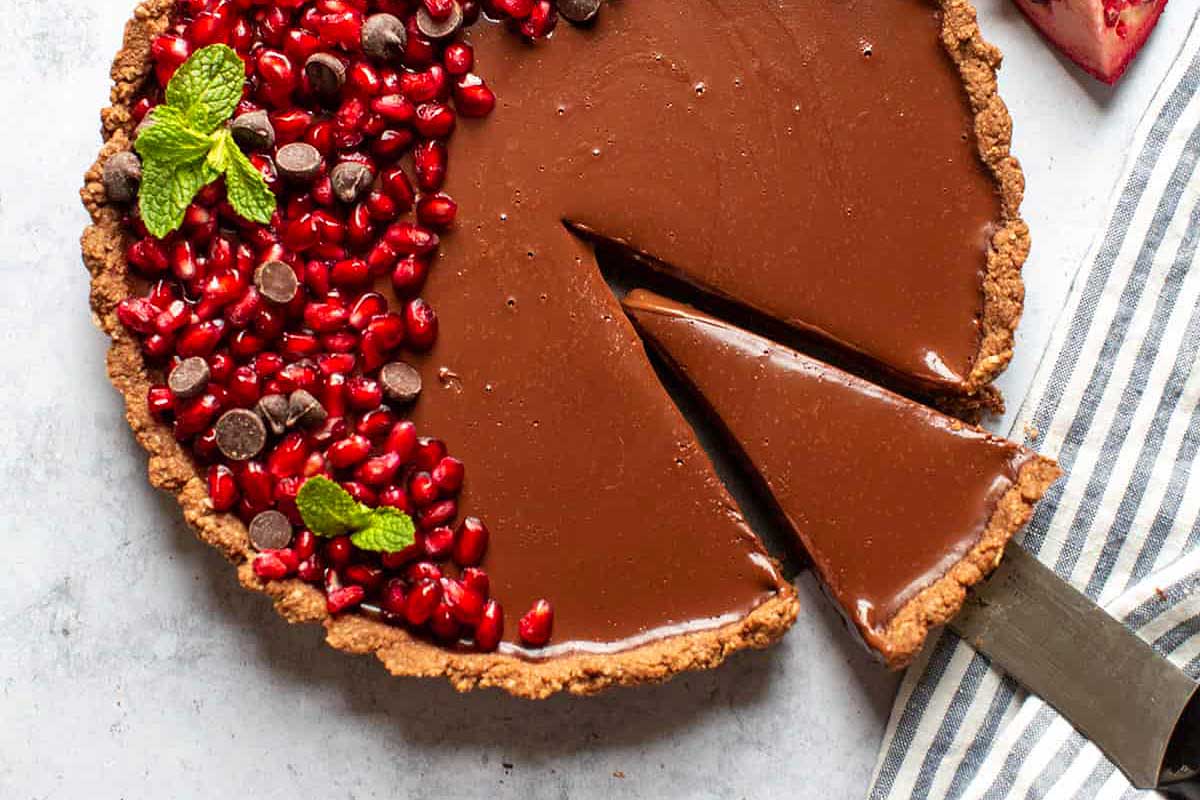 A decadent chocolate pomegranate tart, showcasing a tantalizing slice.