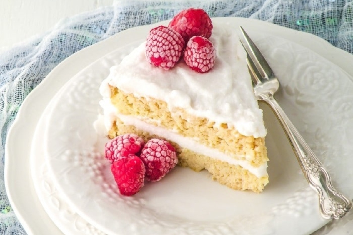 A slice of cake with raspberries on a plate.